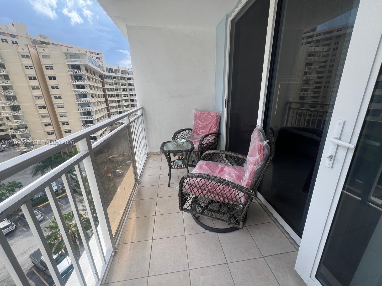Private balcony featuring neutral ceramic tile flooring and a white metal safety railing