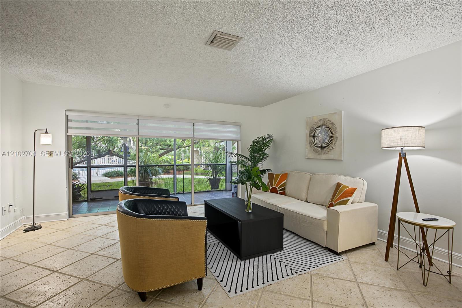 Living area featuring large-format diagonal tile flooring, neutral wall tones, and floor-to-ceiling sliding glass doors opening to a screened enclosure