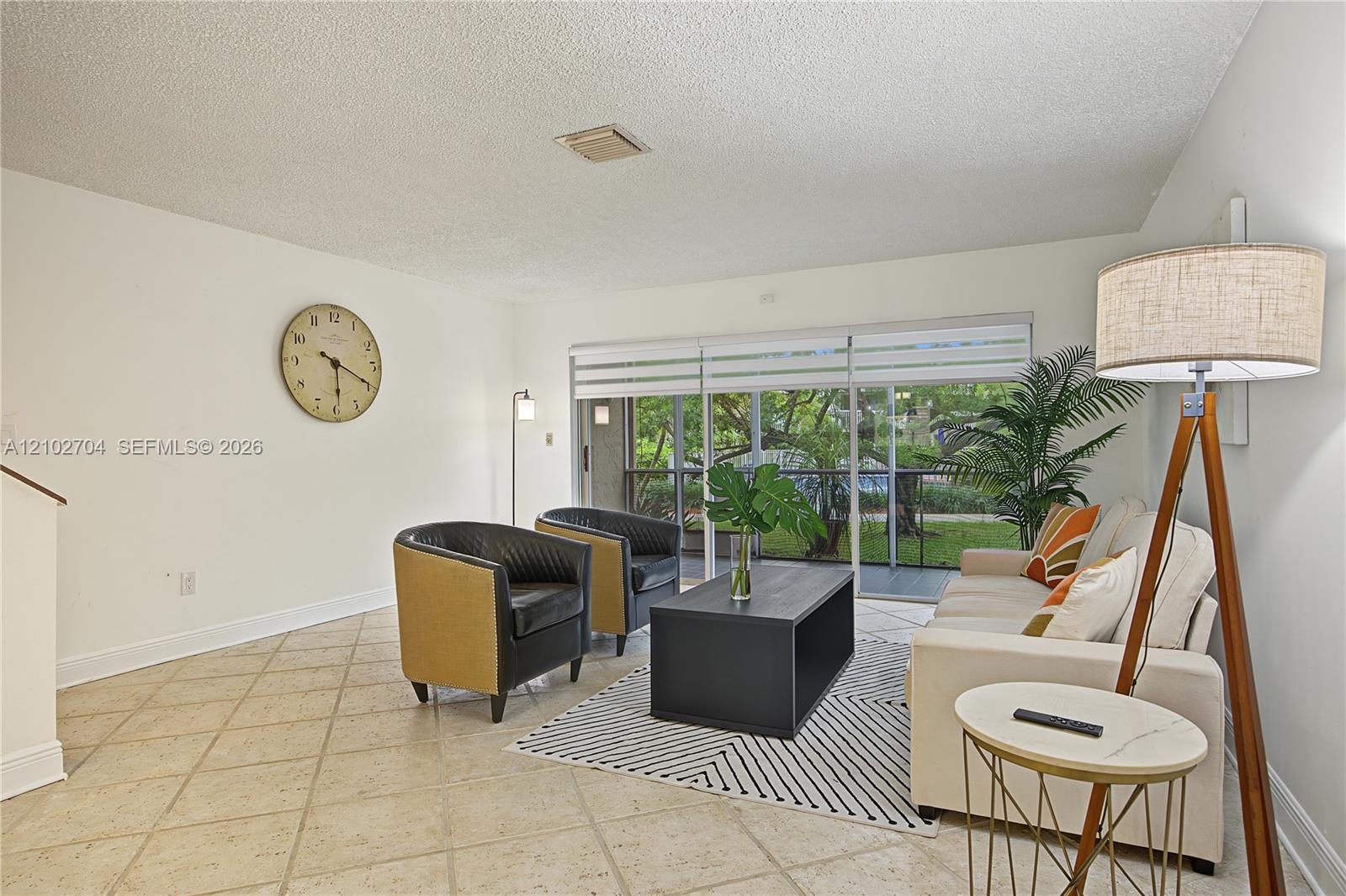 Living area featuring large-format diagonal tile flooring and sliding glass doors opening to an exterior screened enclosure