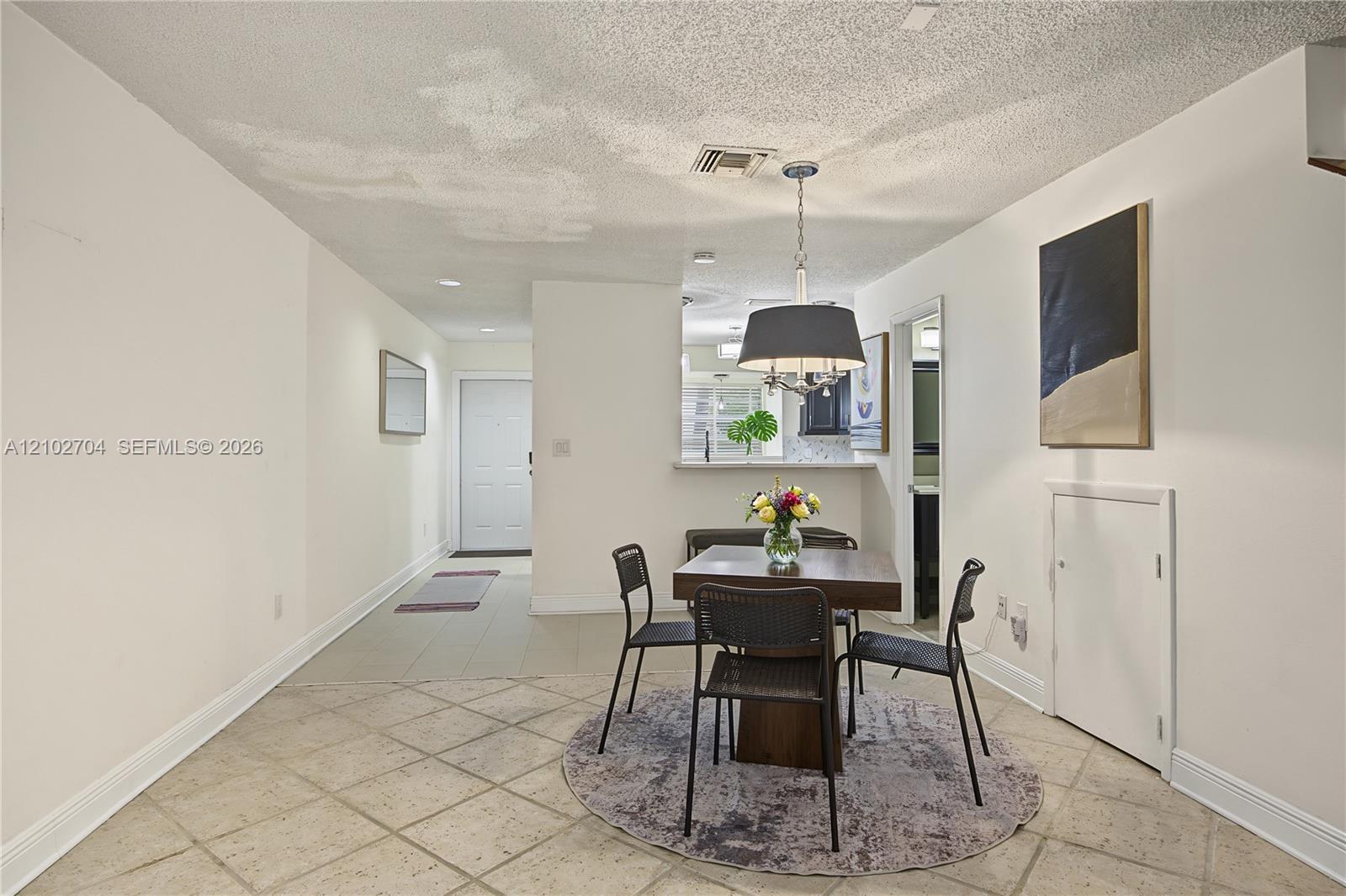 Interior space featuring large-format diagonal tile flooring, a pass-through opening to the kitchen, and a drum-style pendant light fixture