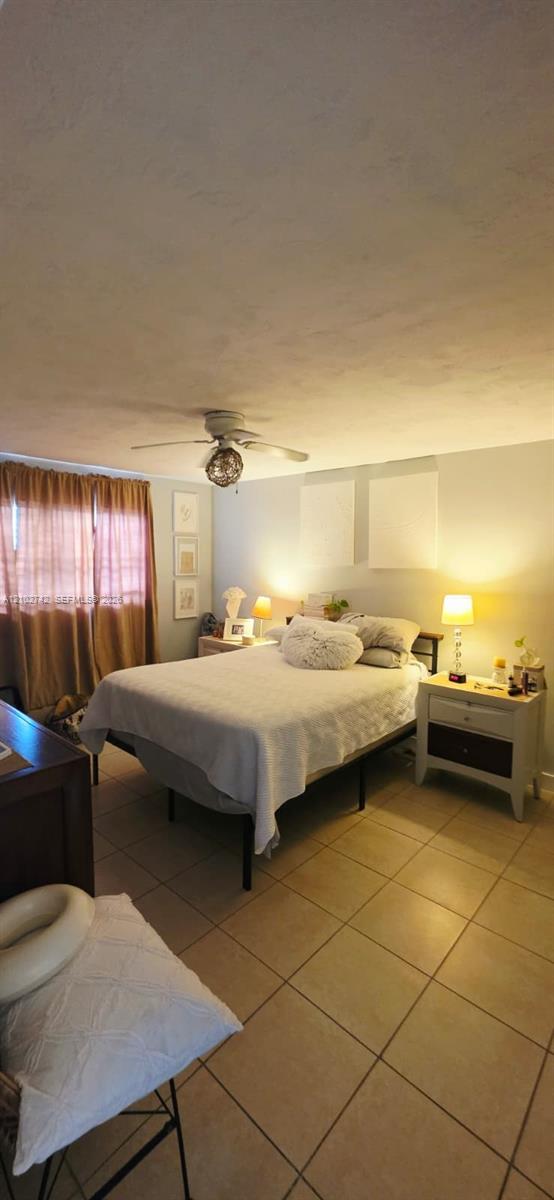 Neutral tile flooring, ceiling fan with integrated lighting, and window treatments