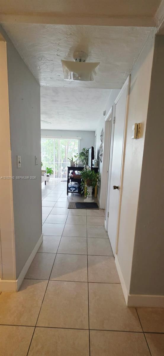 Ceramic tile flooring, neutral wall tones, flush-mount ceiling light fixture, and interior doors