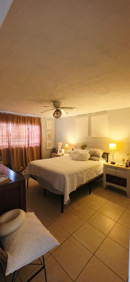 Neutral-toned room featuring oversized tile flooring and a ceiling-mounted light fixture with integrated fan