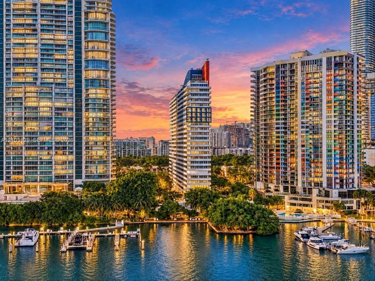 High-rise urban architecture featuring floor-to-ceiling glass facades, private balcony tiers, extensive waterfront bulkhead, and deep-water boat slips
