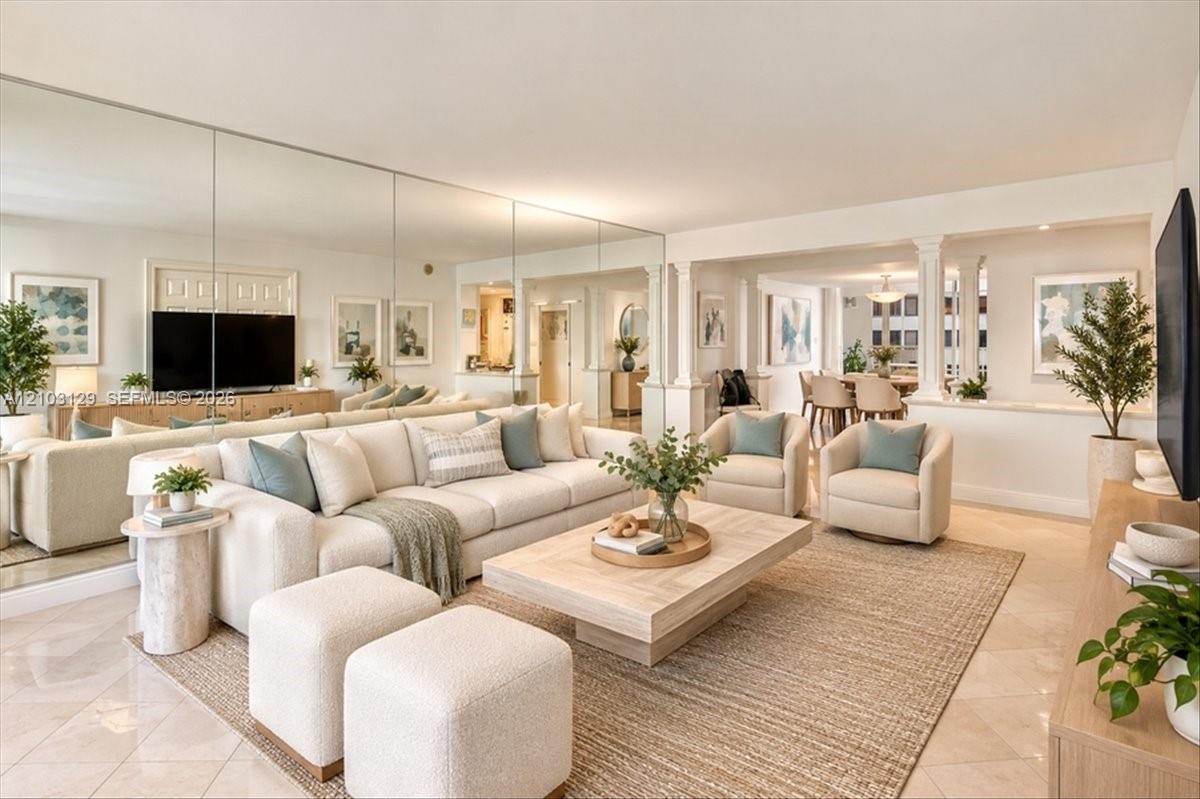 Living room featuring full-wall decorative mirrors, polished tile flooring, and architectural columns