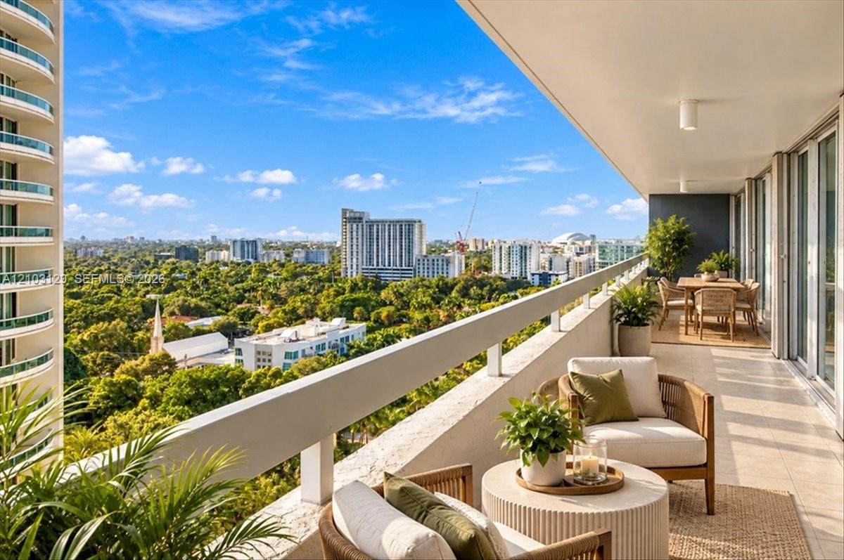 Expansive covered terrace featuring tiled flooring, a continuous metal safety railing, and panoramic cityscape and canopy scenery