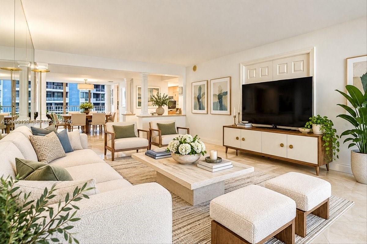 Open-concept interior featuring light-toned stone tile flooring, structural columns, and mirrored wall accents
