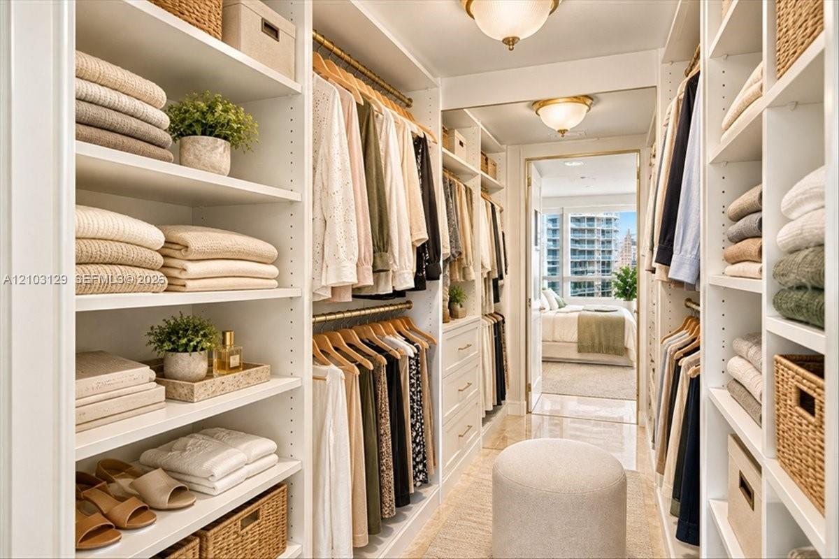 Custom walk-in closet featuring extensive built-in white shelving, integrated hanging rods, recessed drawer storage, and two flush-mount ceiling light fixtures