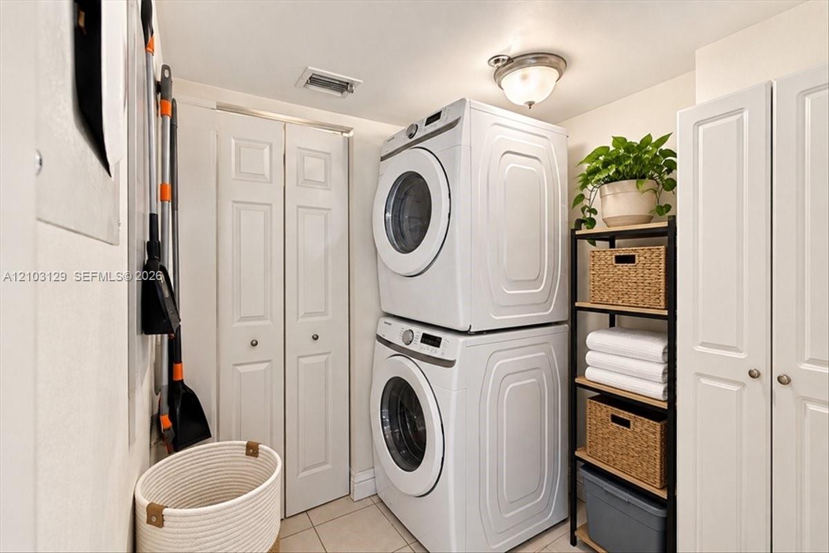 Laundry area featuring floor-to-ceiling white paneled storage cabinetry, tile flooring, and a flush-mount dome light fixture