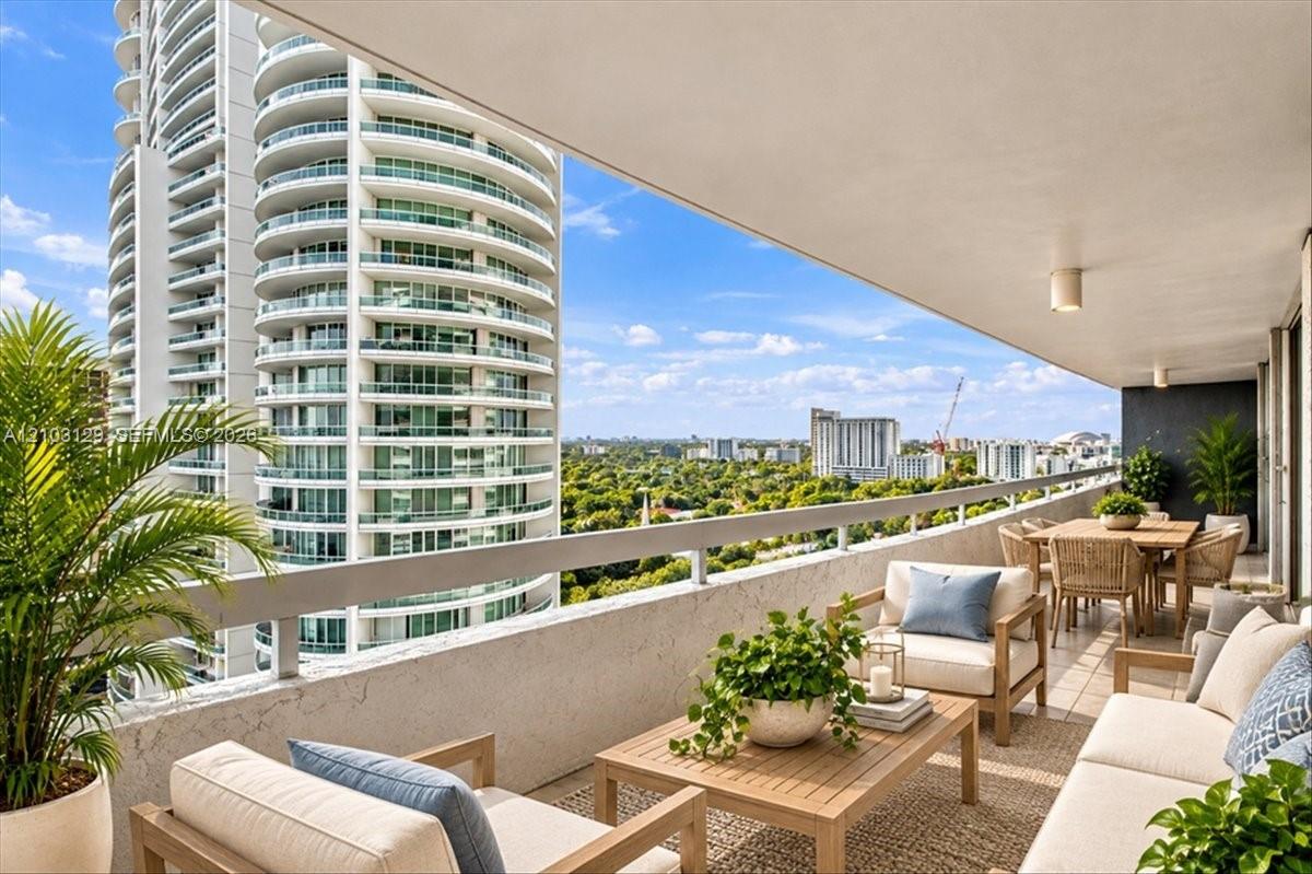 Expansive covered balcony featuring a concrete perimeter railing, recessed ceiling lighting, and large-format tile flooring