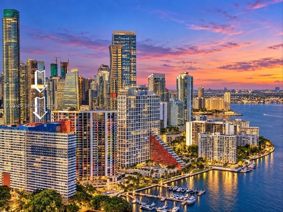 High-rise residential building featuring an urban skyline backdrop, water frontage, and balcony space