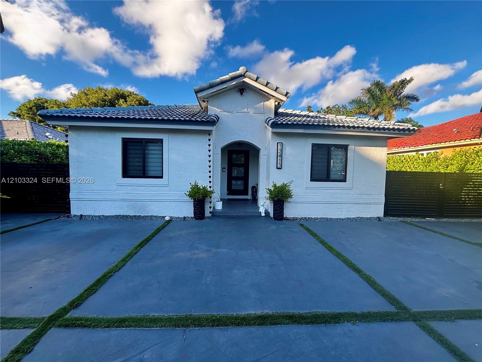 Stucco exterior with a tiled roof, arched entryway, and a concrete driveway featuring inlaid grass borders Stucco exterior with a tiled roof, arched entryway, and a concrete driveway featuring inlaid grass borders