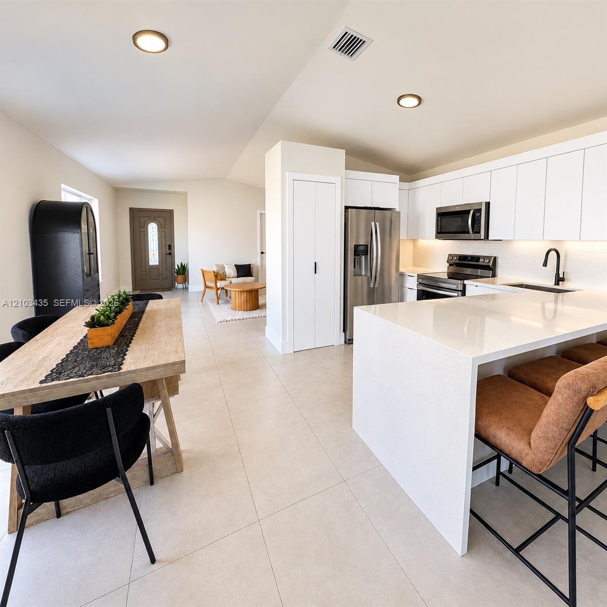 Modern kitchen featuring a waterfall-edge stone island, white flat-panel cabinetry, stainless steel appliances, and large-format tile flooring Modern kitchen featuring a waterfall-edge stone island, white flat-panel cabinetry, stainless steel appliances, and large-format tile flooring