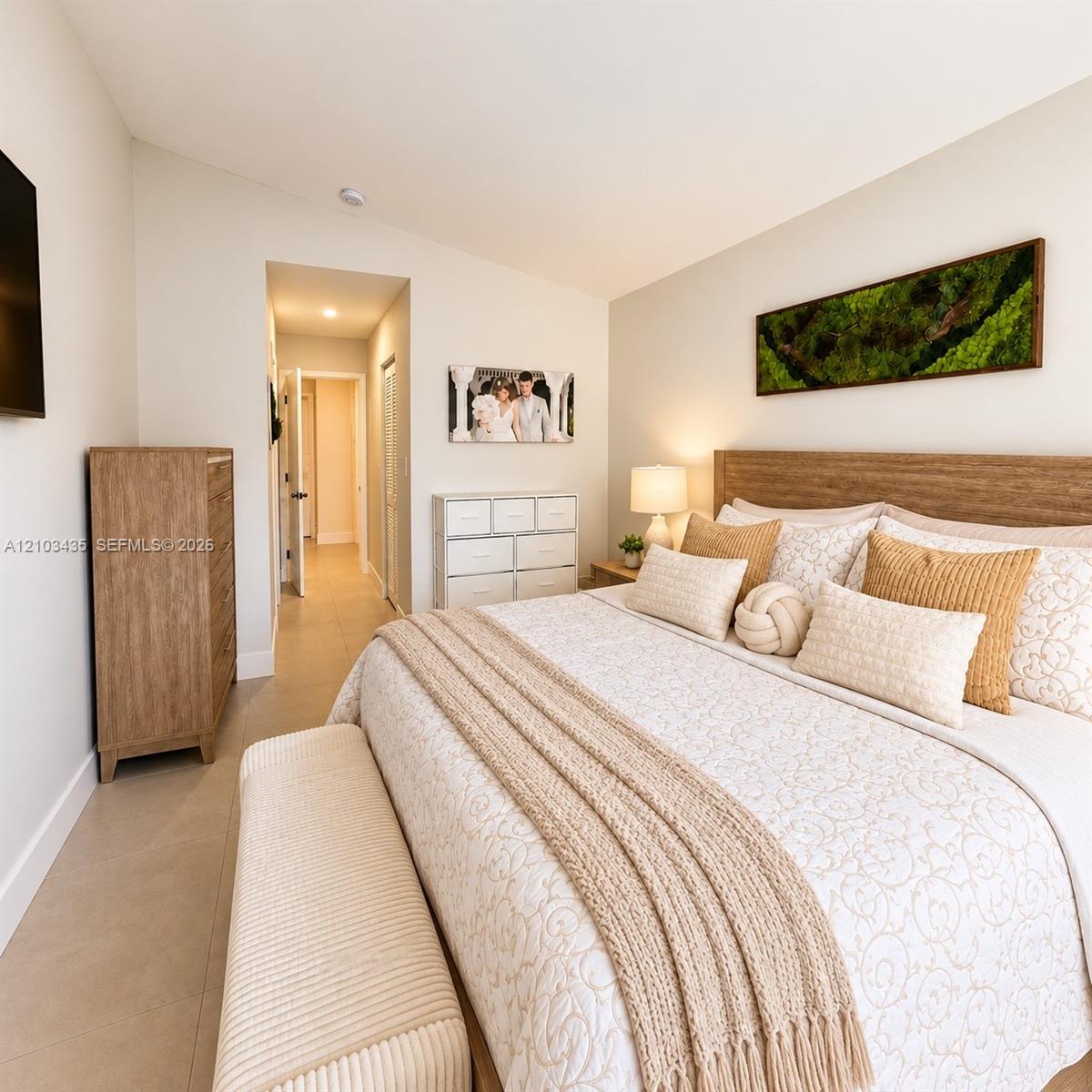 Neutral-toned interior space featuring light-colored tile flooring, a slanted ceiling, and a built-in wood-finish headboard Neutral-toned interior space featuring light-colored tile flooring, a slanted ceiling, and a built-in wood-finish headboard