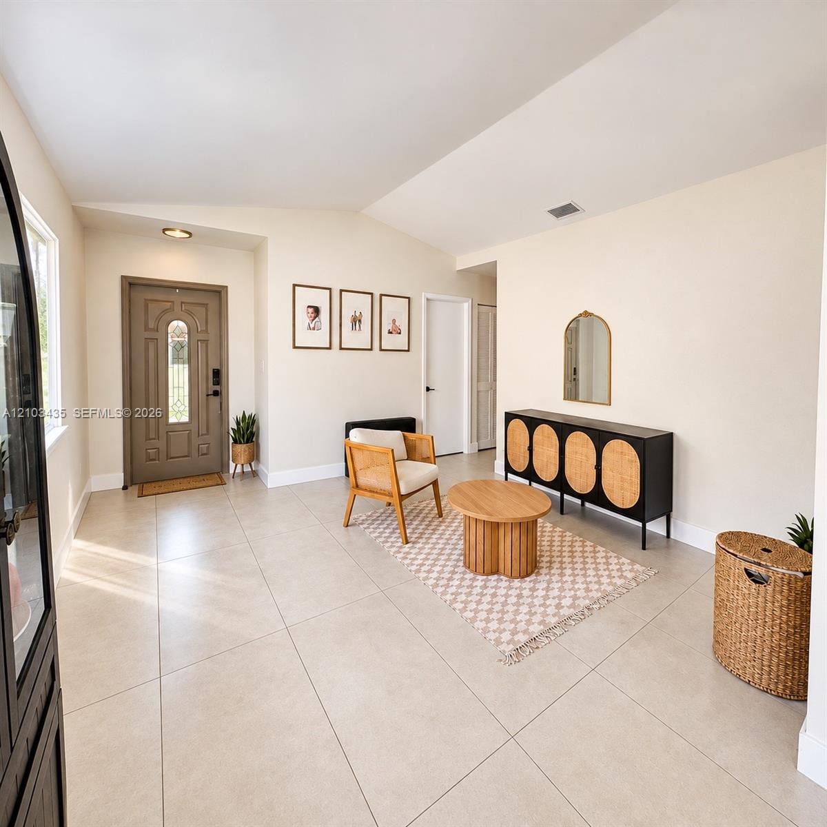 Entryway featuring large-format neutral floor tile, vaulted ceilings, and a paneled front door with decorative glass inlay Entryway featuring large-format neutral floor tile, vaulted ceilings, and a paneled front door with decorative glass inlay