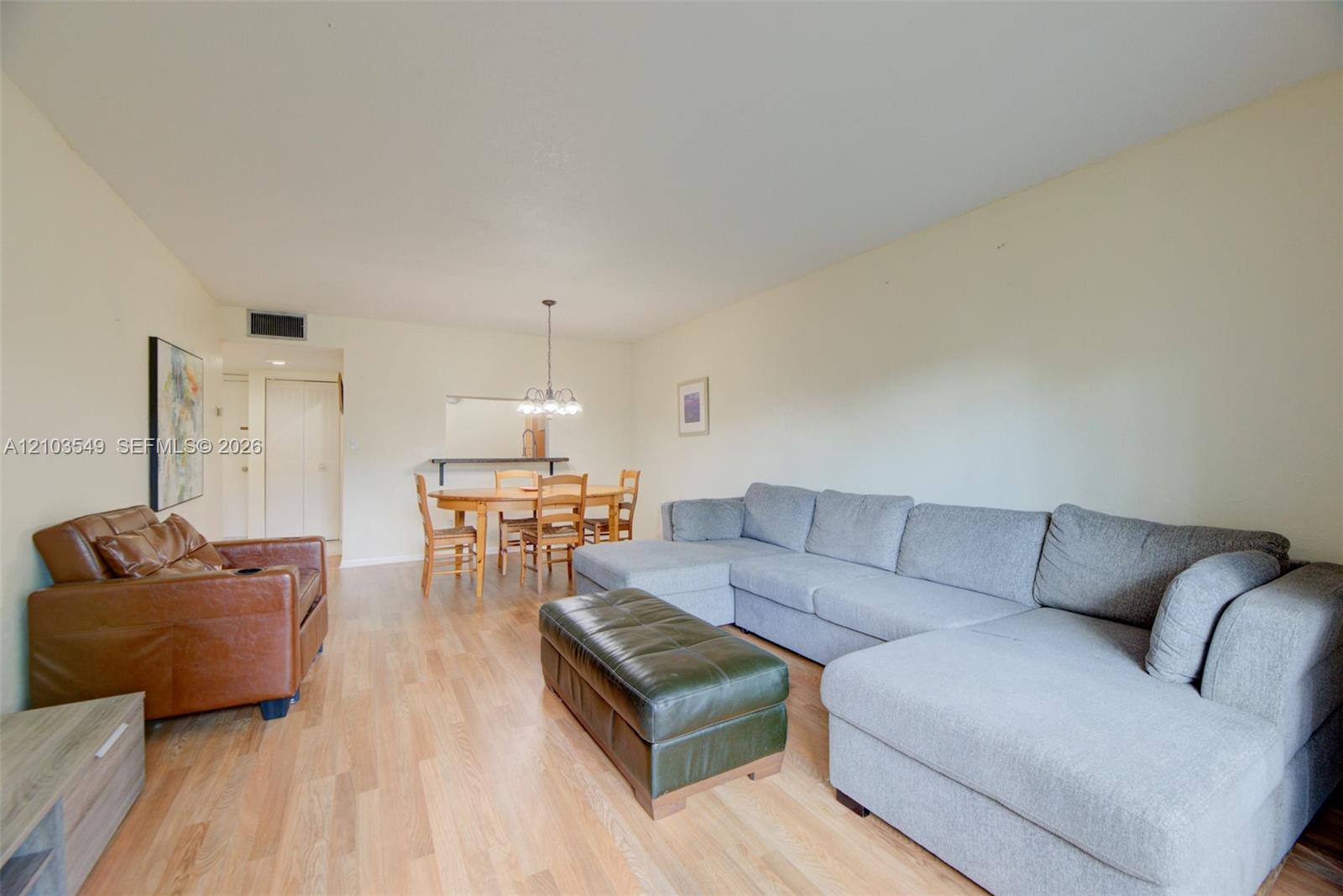 Open-concept living space featuring wood-finish flooring and a central pendant light fixture