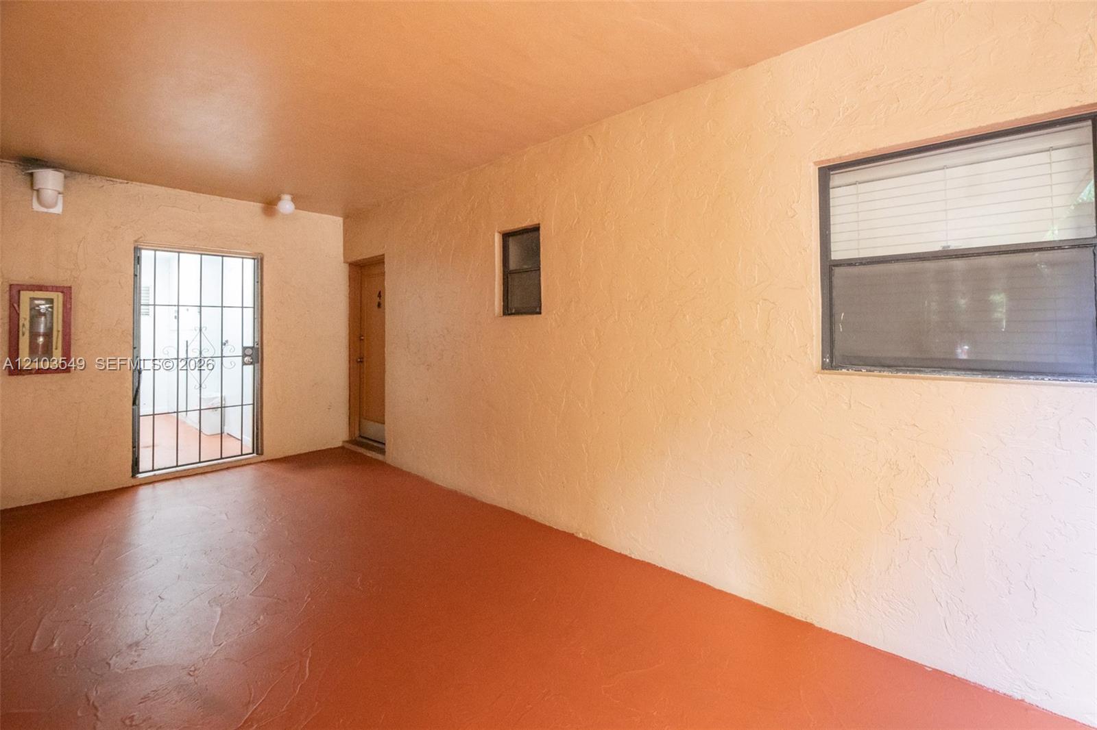 Covered patio featuring textured wall finishes, solid flooring, a horizontal sliding window, and a metal security screen door