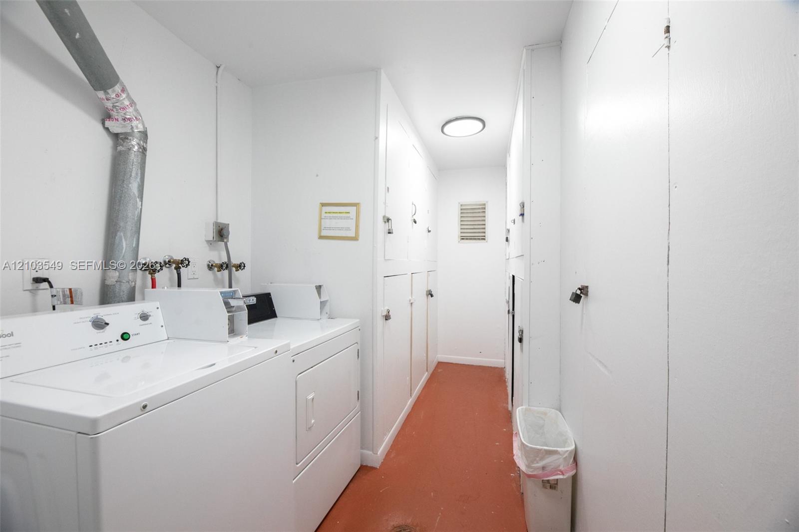 Utility space featuring extensive floor-to-ceiling cabinetry, laundry machines, and solid-finish flooring