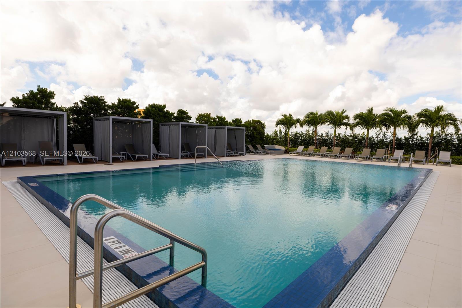 Swimming pool with integrated metal handrails, expansive tile surround, and multiple permanent poolside cabanas