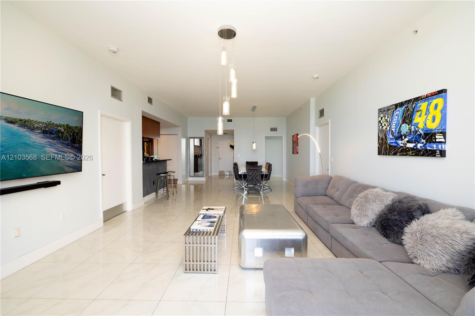 Open-concept interior featuring large-format tile flooring, recessed ceiling lighting, and a multi-pendant light fixture