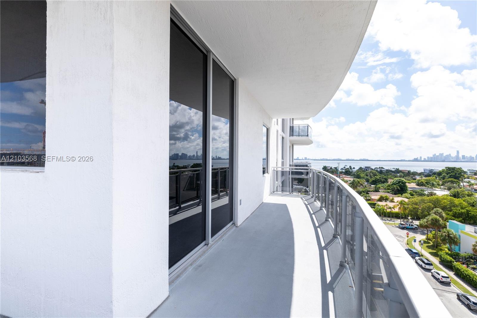 Curved balcony featuring a metal railing, concrete flooring, and full-height sliding glass doors