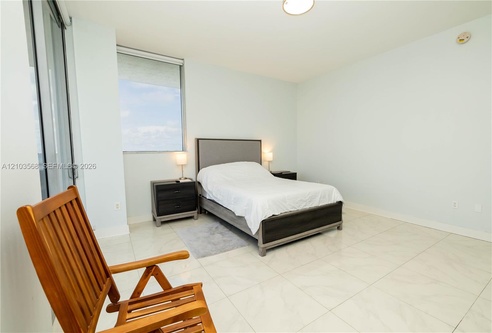 Large-format tile flooring, expansive window, and ceiling-mounted lighting fixture