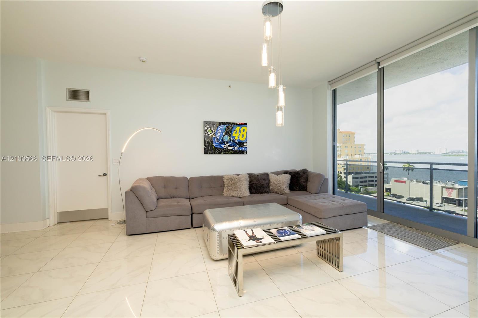 Large-format tile flooring, floor-to-ceiling glass panel windows, and a multi-pendant light fixture