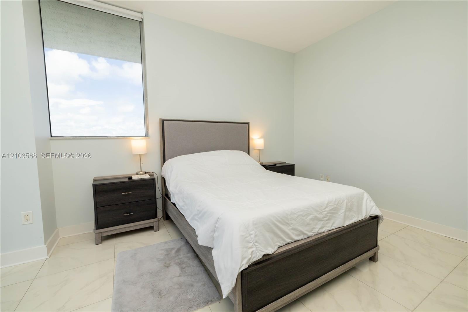 Light-filled room featuring polished tile flooring and a large floor-to-ceiling window