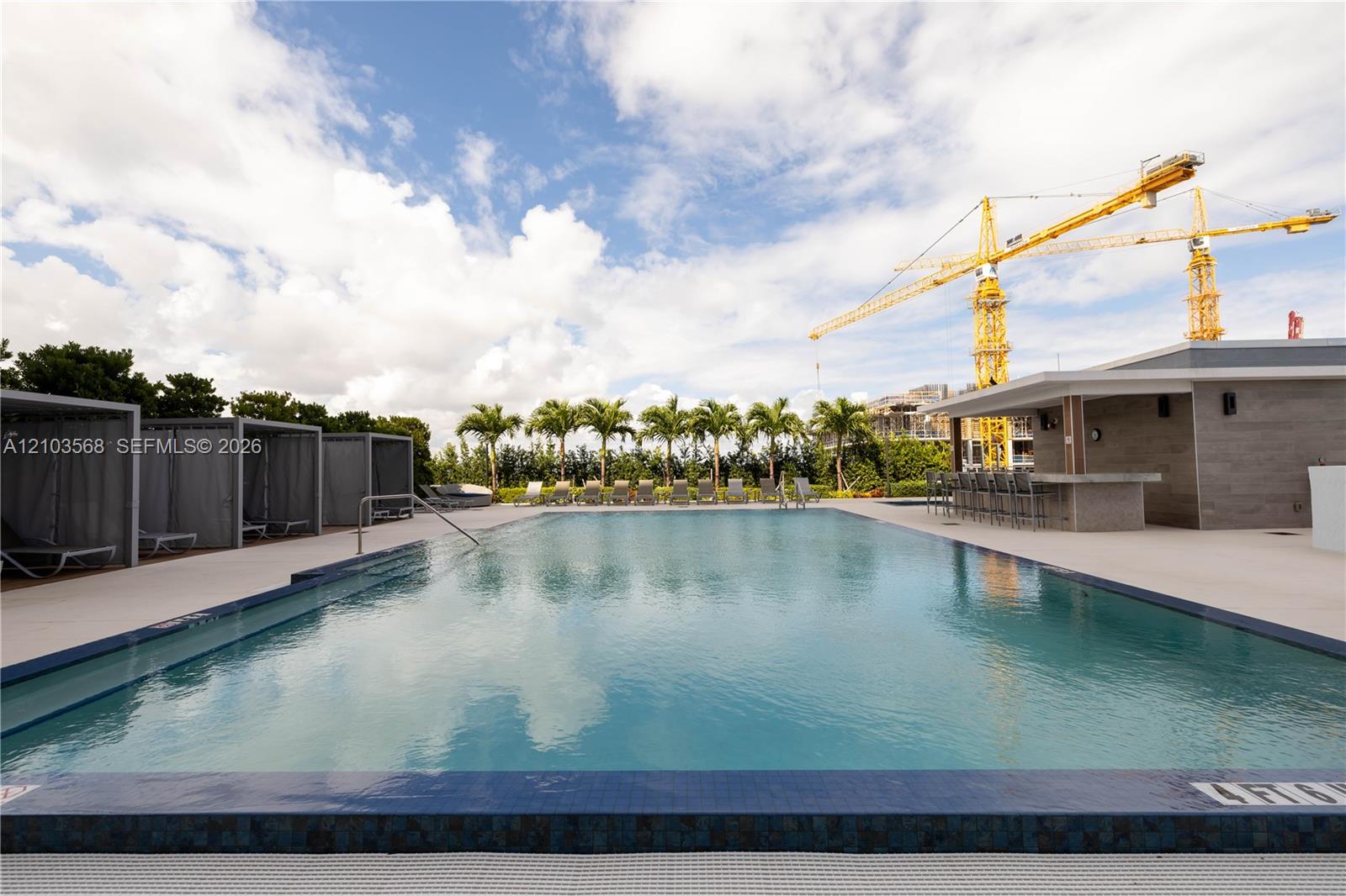 Swimming pool with tile edging, paved deck, multiple cabanas, and integrated outdoor bar area