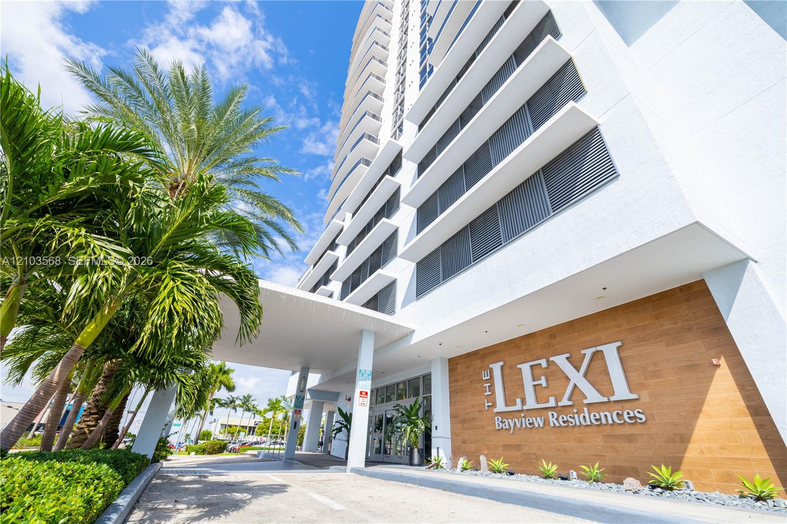 High-rise exterior featuring a covered porte-cochre, wood-finish wall cladding, private balconies with horizontal railings, and integrated structural pillars
