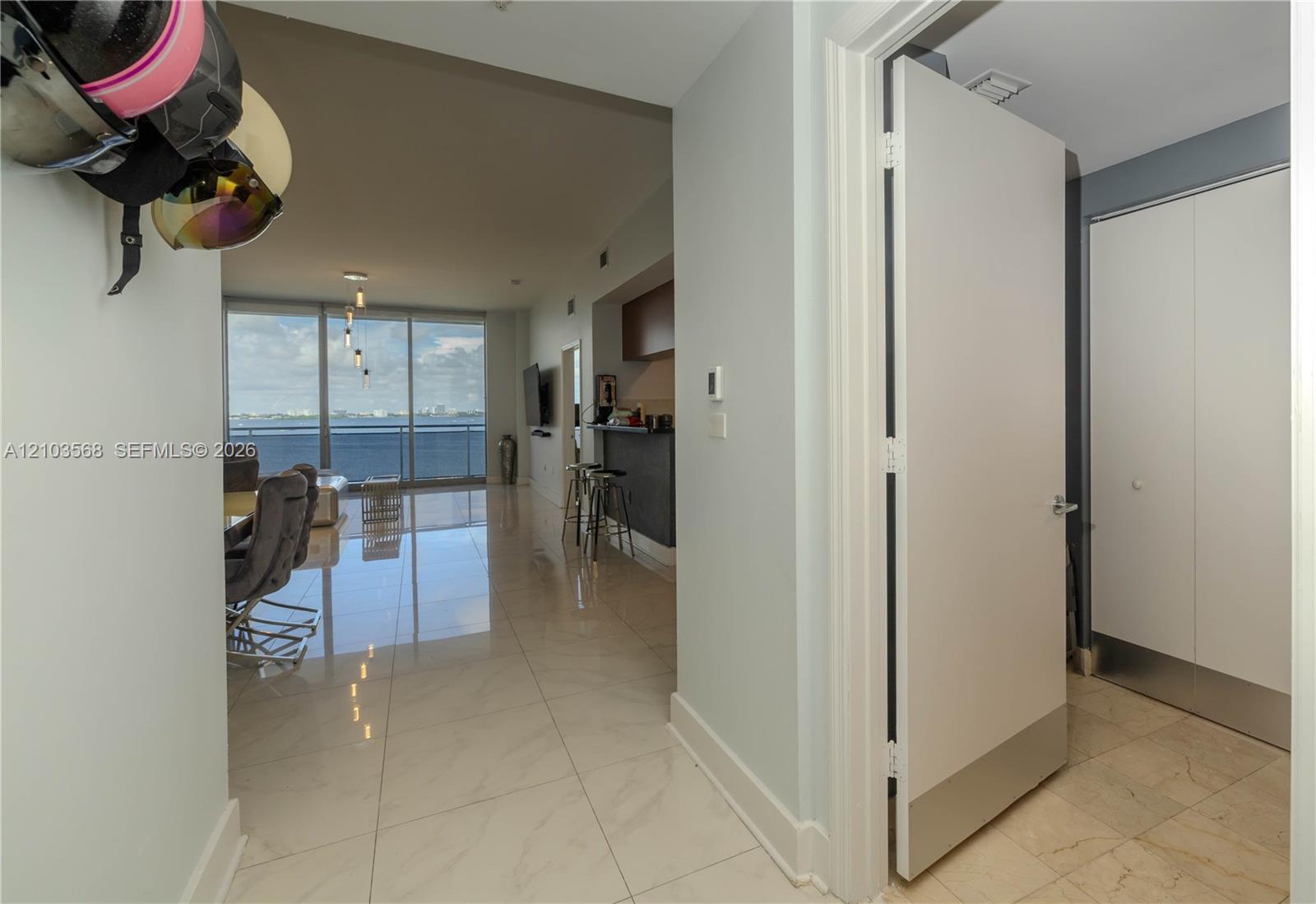 Interior entryway featuring large-format light-toned tile flooring, floor-to-ceiling windows, and built-in closet storage with white flat-panel doors