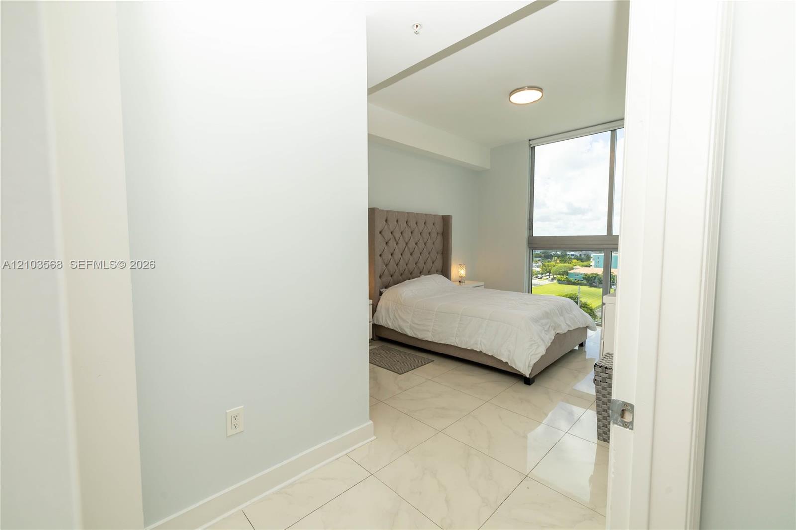 Room featuring stone-finish tile flooring, floor-to-ceiling windows, and a flush-mount ceiling light fixture