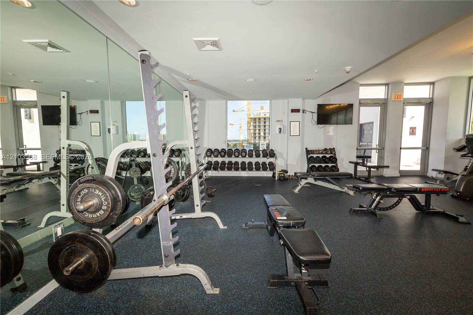 Fitness facility featuring wall-to-wall mirrors, durable rubberized flooring, and recessed ceiling lighting