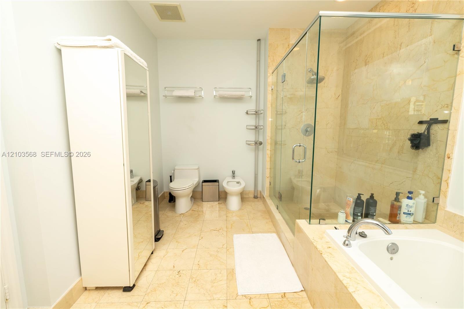 Bathroom featuring a stone-tile floor, a glass-enclosed shower with stone-tile surround, and a drop-in soaking tub
