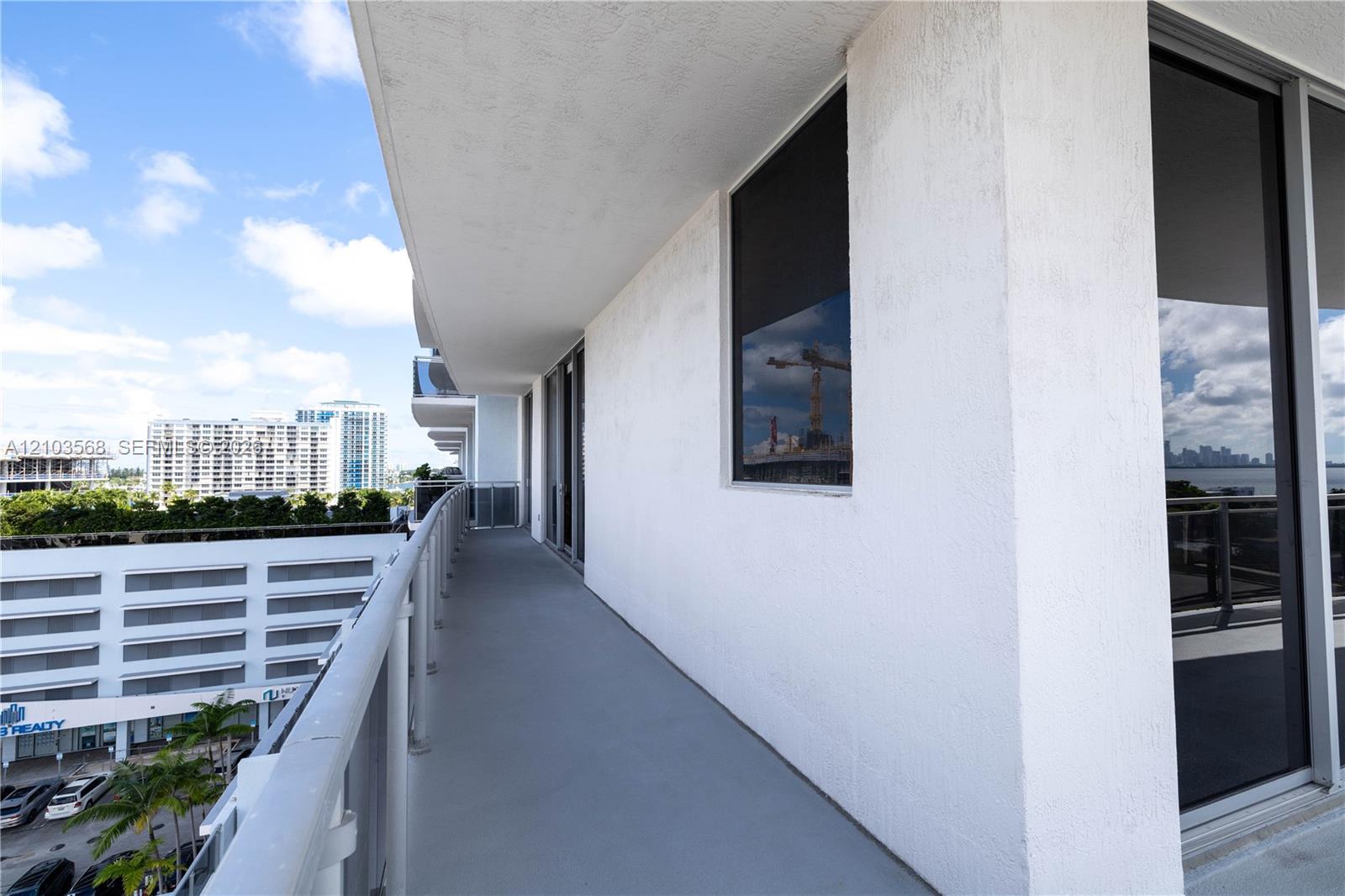 Covered private balcony featuring concrete flooring, stucco wall finish, and metal railing with glass inserts