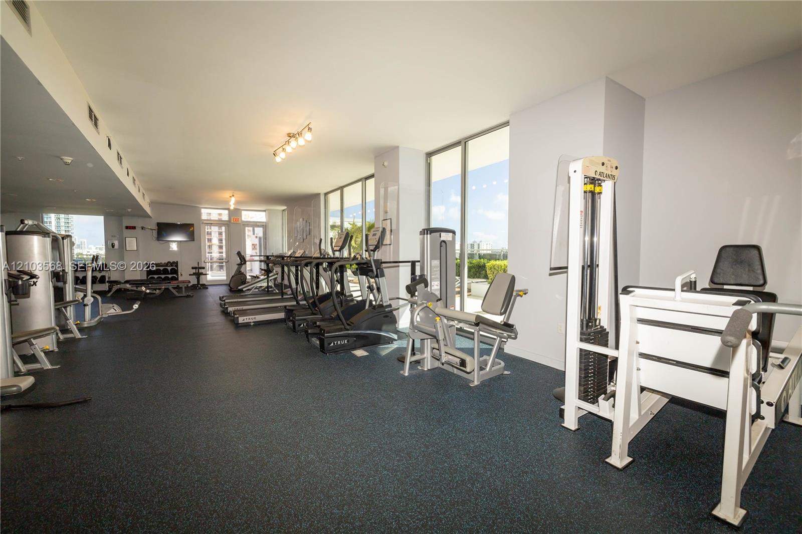 Fitness center featuring floor-to-ceiling windows, rubberized flooring, and recessed lighting