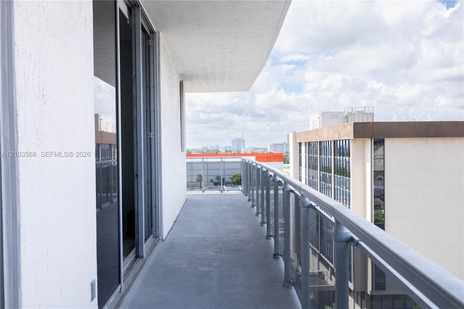 Private balcony featuring concrete flooring and a metal railing with glass panels