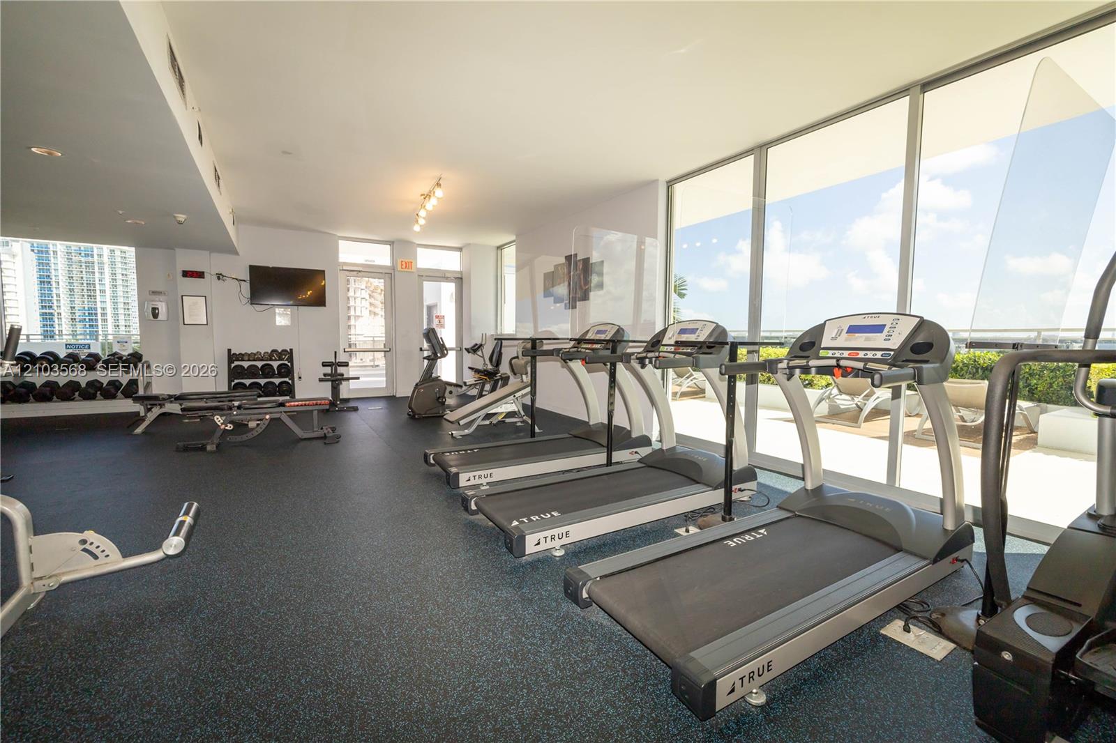 Fitness center featuring rubber flooring, floor-to-ceiling windows, and track lighting