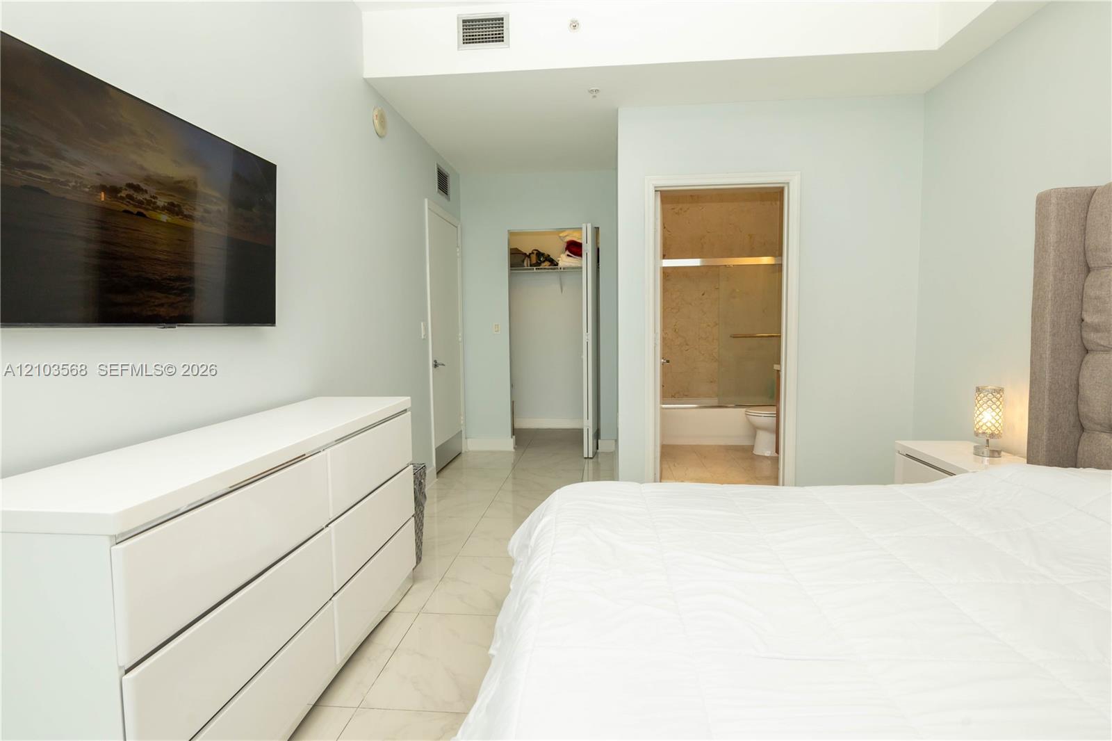 Polished stone-finish flooring, walk-in closet with built-in shelving, and neutral wall tones