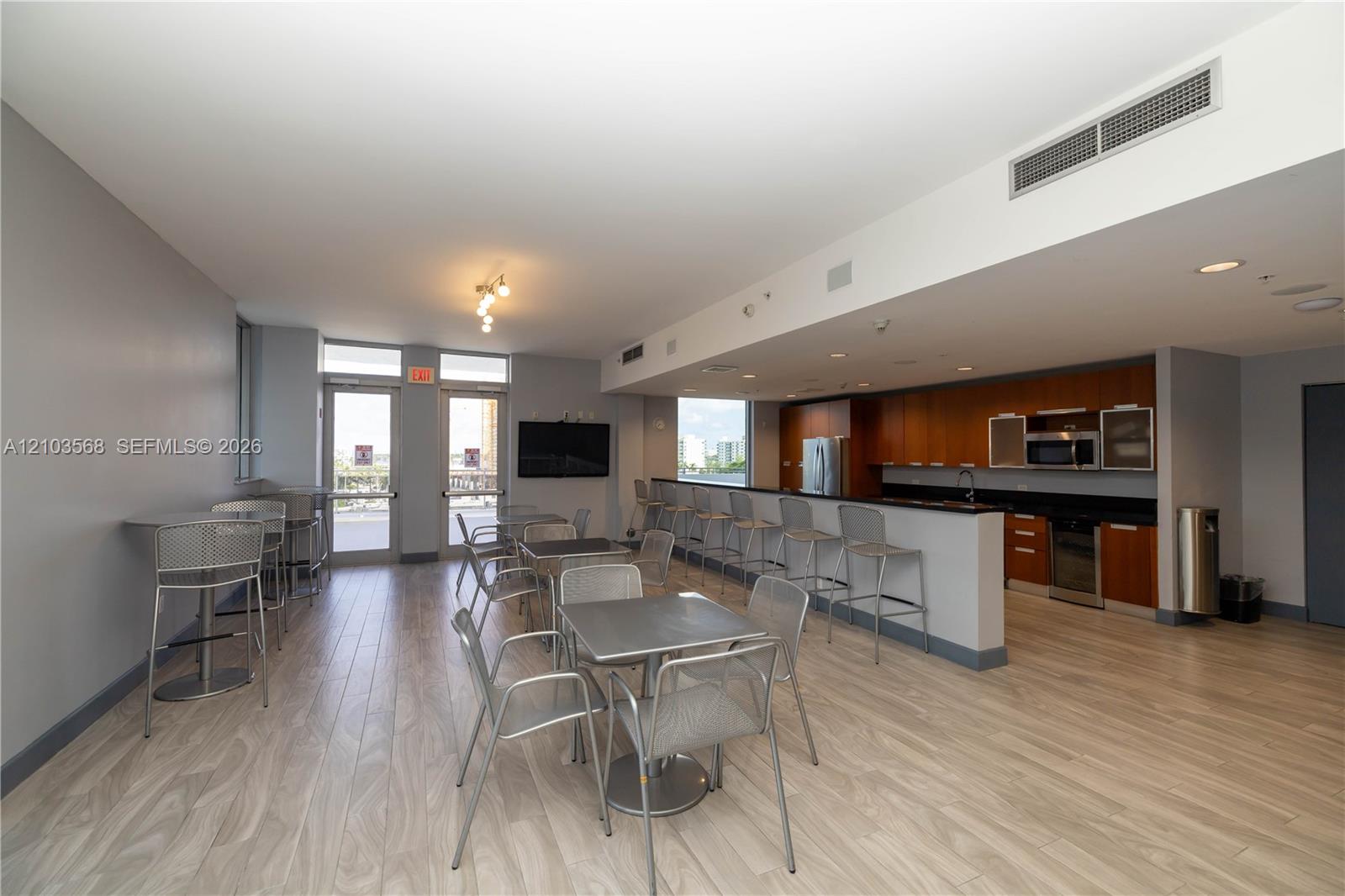 Kitchen area featuring wood-finish cabinetry, dark solid-surface countertops, and stainless steel appliances, complemented by wood-finish flooring and recessed lighting