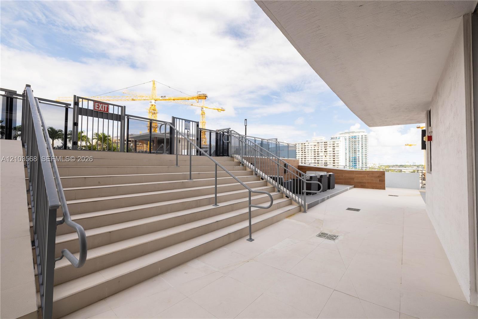 Outdoor terrace featuring light-toned tile flooring, metal railings, and a wide staircase