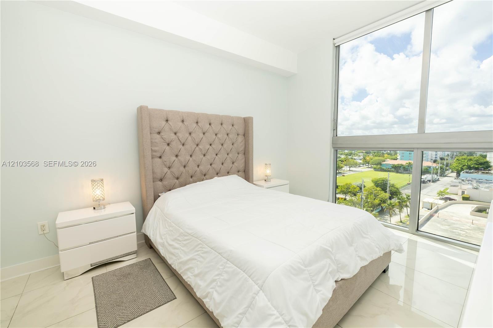 Floor-to-ceiling windows featuring external landscape scenery, polished stone-finish flooring, and high-reaching ceiling height