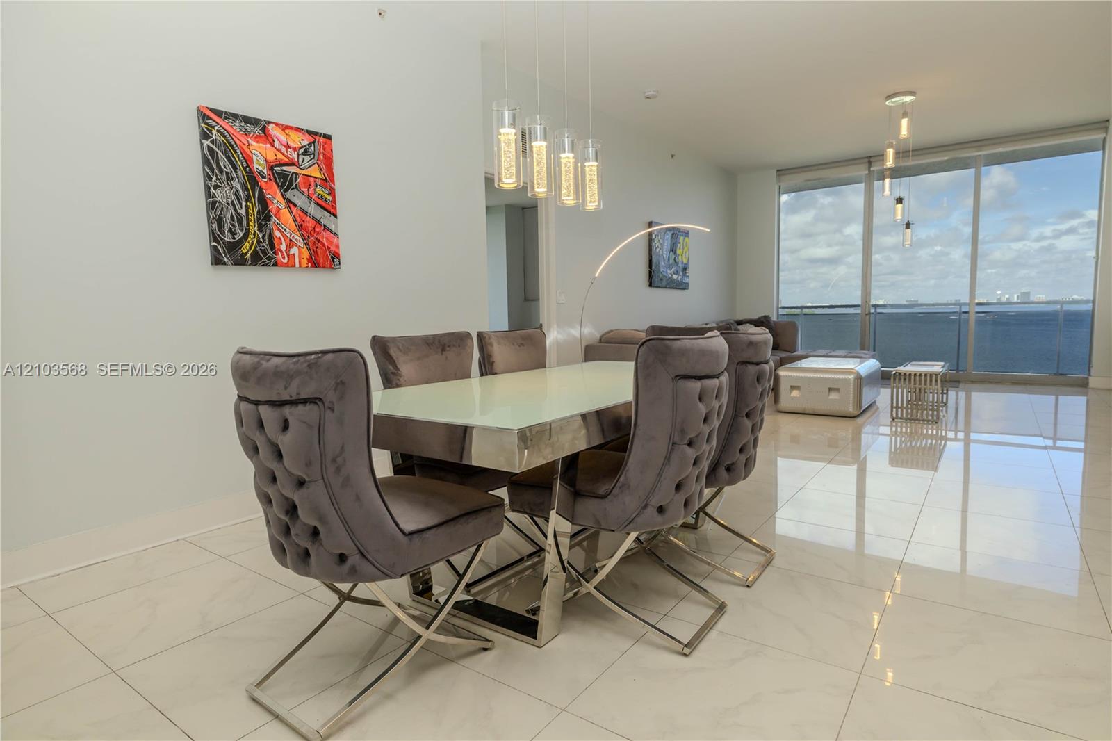 Open-concept living space with polished stone flooring, floor-to-ceiling glass paneling, and multi-pendant lighting fixtures