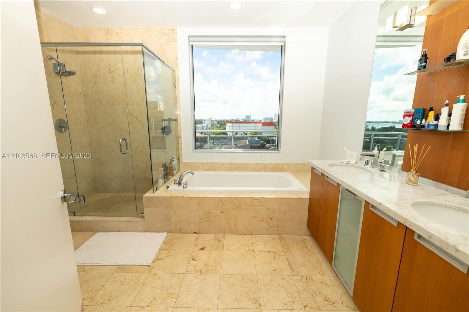 Bathroom featuring a glass-enclosed shower, built-in soaking tub, dual-sink vanity with stone countertop, and wood-finish cabinetry