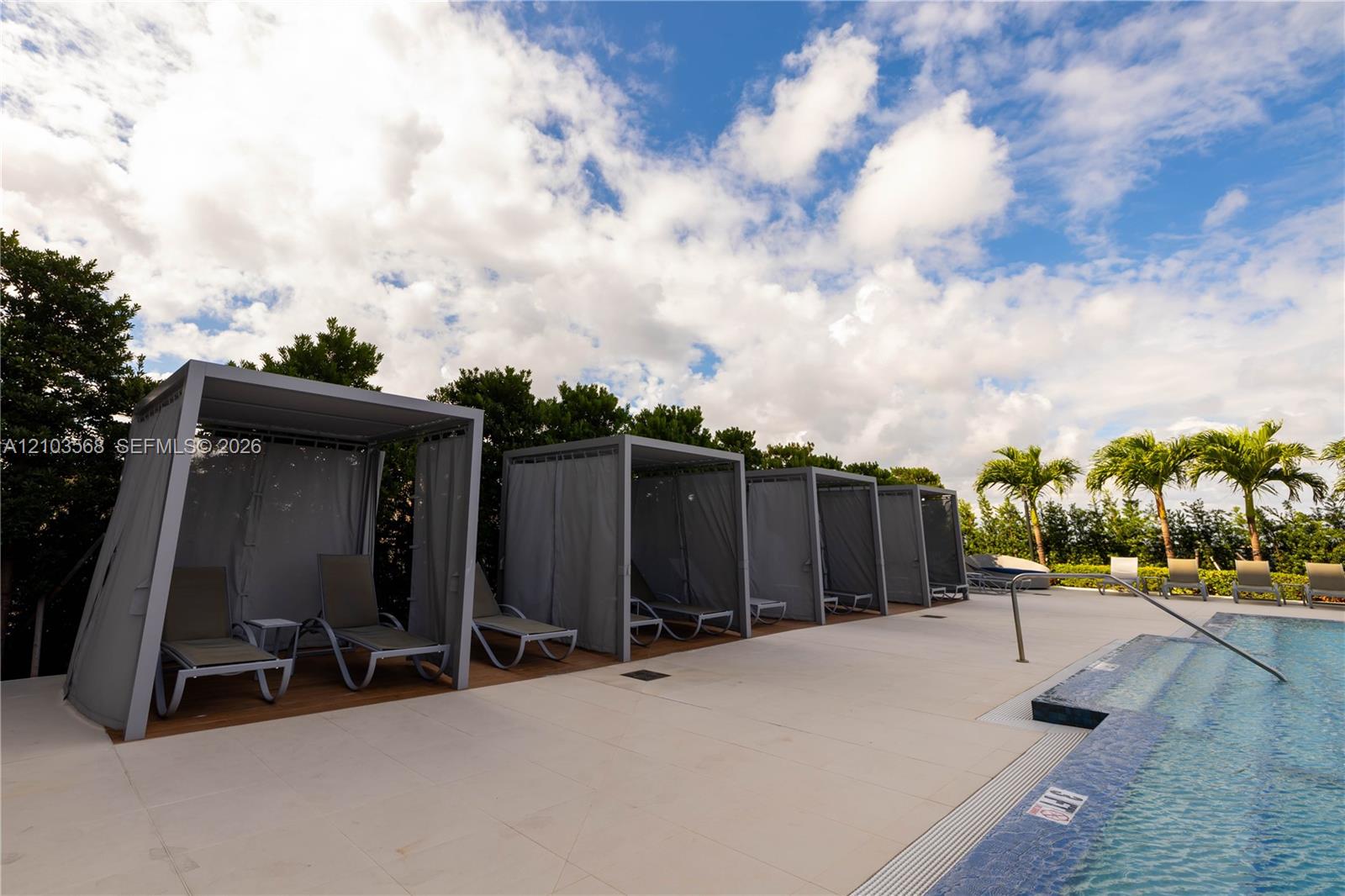 Swimming pool with tiled waterline, concrete pool deck, and integrated shaded cabanas