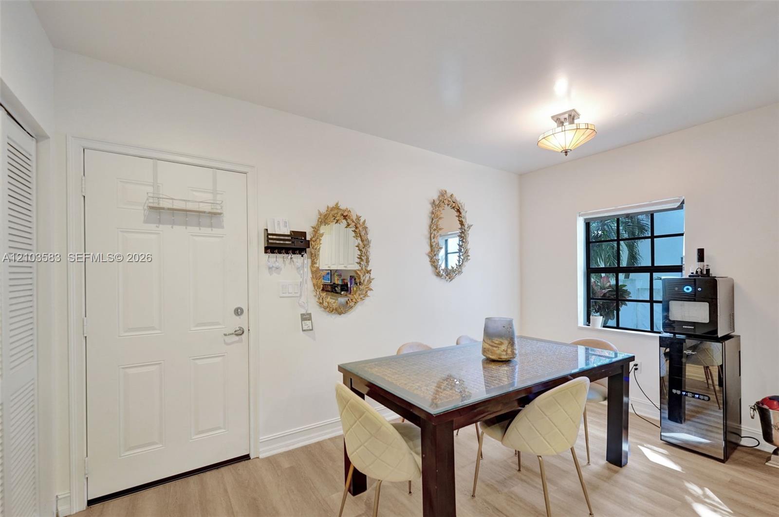 Multi-pane grid window, wood-finish flooring, six-panel interior door, and semi-flush mount glass ceiling fixture