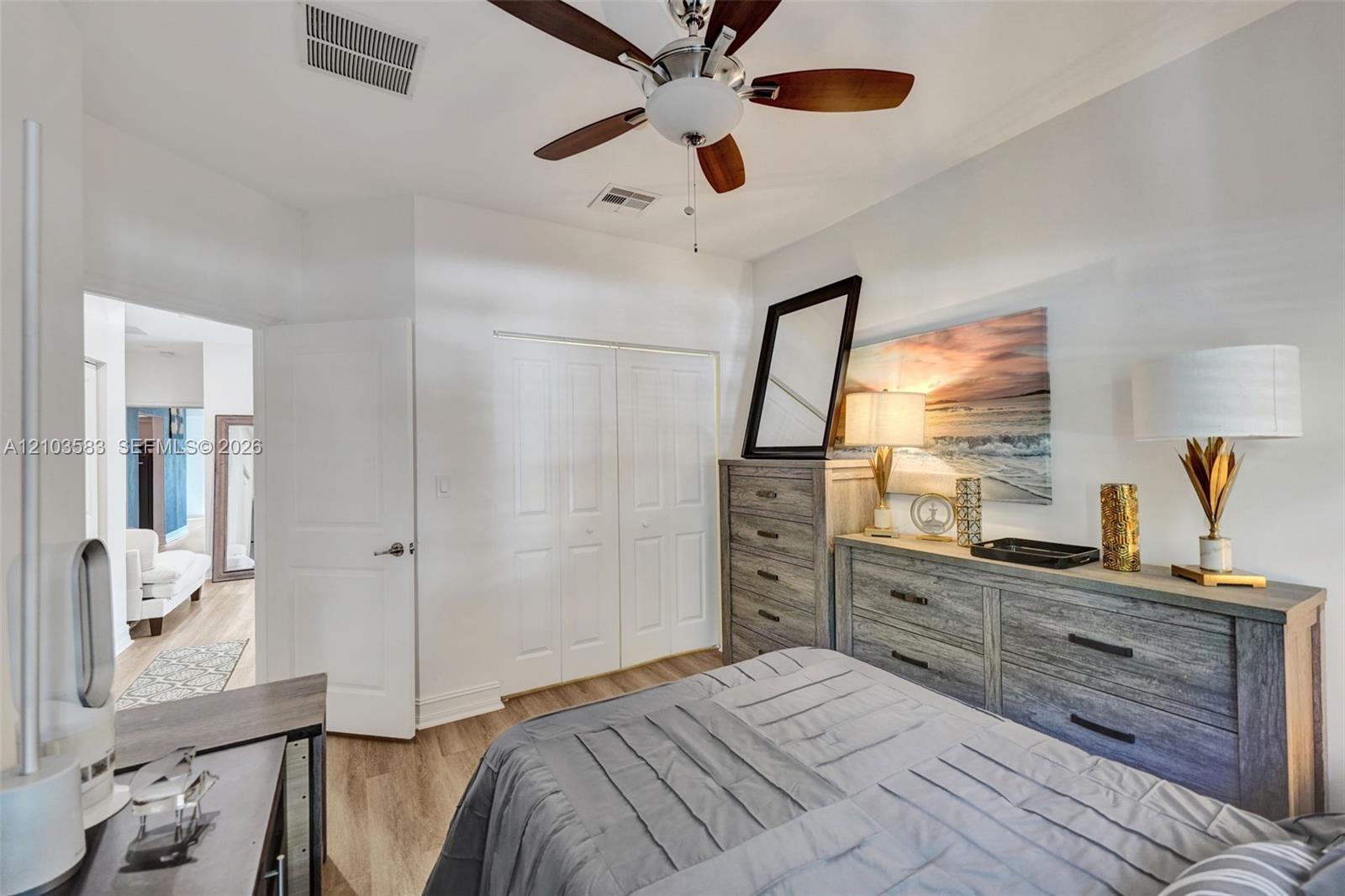 Bedroom featuring wood-finish flooring, a ceiling fan with integrated lighting, and a double-door reach-in closet
