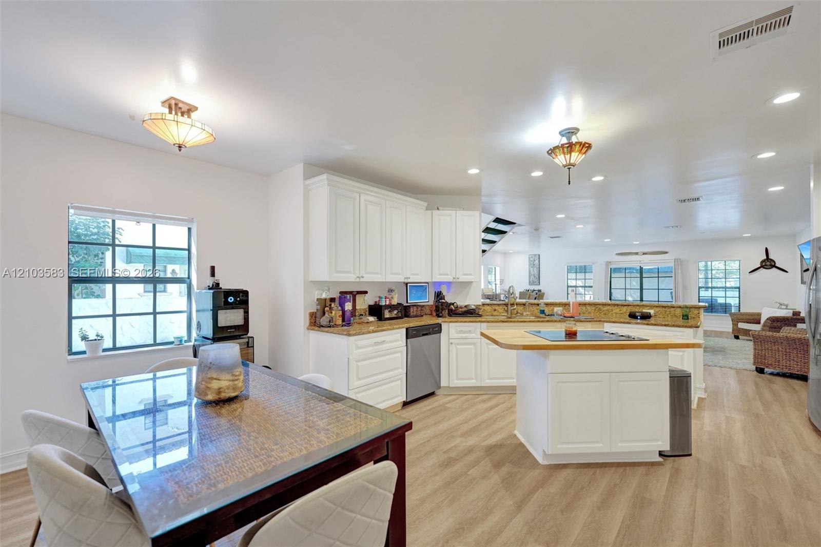 Kitchen featuring white shaker cabinetry, stone countertops, a central island with an integrated cooktop and wood-topped counter, and wood-finish flooring