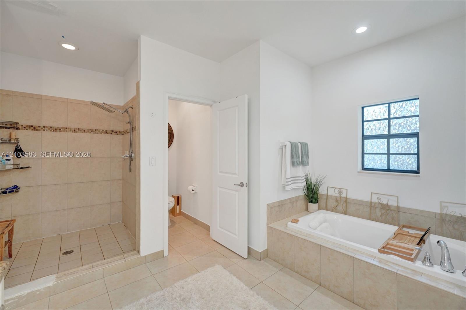 Bathroom featuring a tile-surround walk-in shower with a mosaic accent border, a built-in soaking tub with tile surround, recessed lighting, and large-format tile flooring