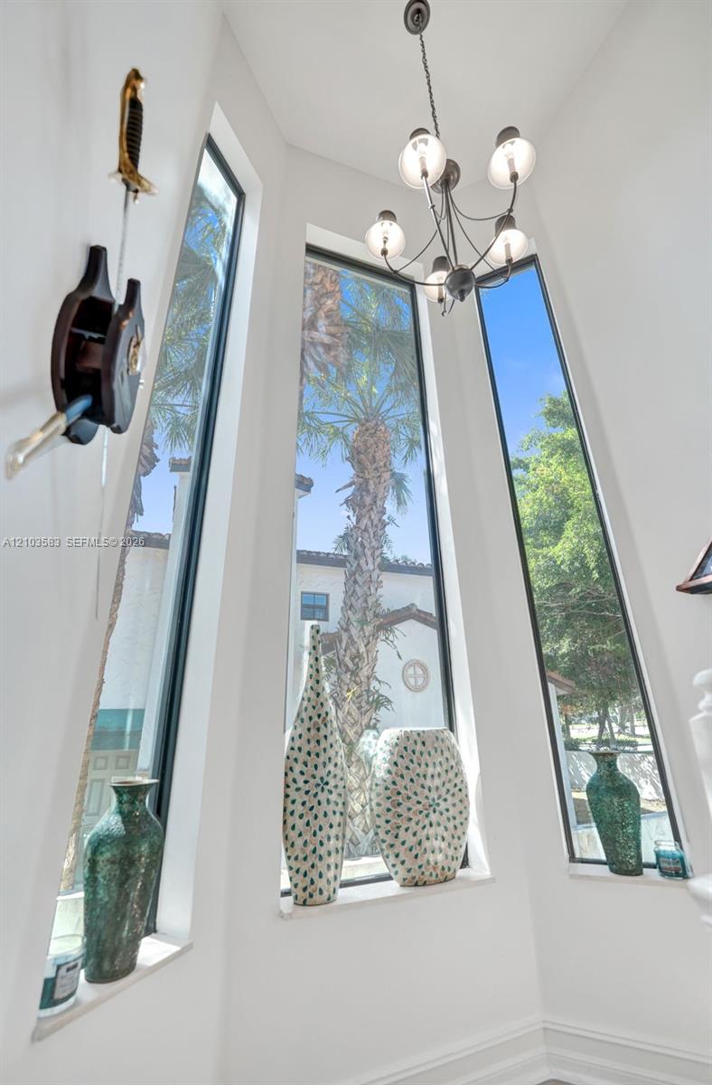 Multi-story bay windows with dark frames, tall fixed-pane glass, and a multi-arm metal chandelier